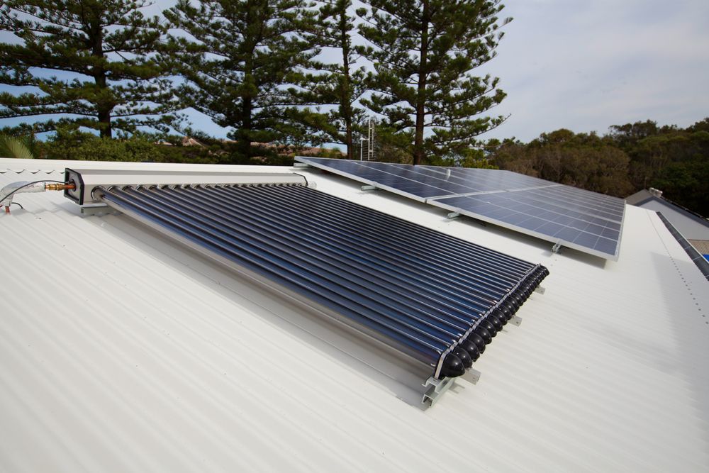 A Man Is Installing Solar Panels On The Roof Of A Building — Forster Solar and Lighting In Pacific Palms, NSW