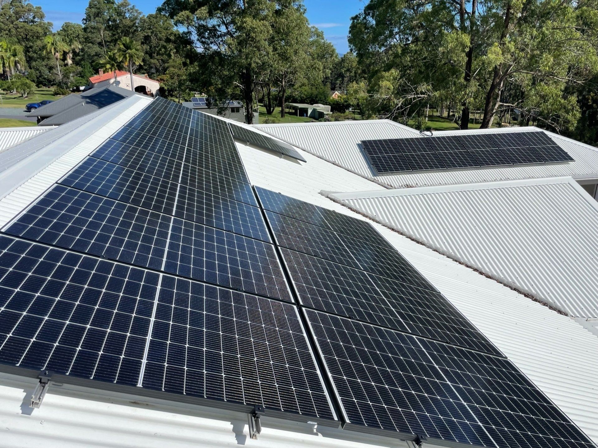 A Man Is Working On A Solar Panel On Top Of A Roof — Forster Solar and Lighting In Tuncurry, NSW