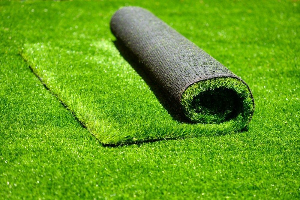 Roll of Artificial Green Turf Partially Unrolled on A Grassy Surface — Banksia Turf in Forster, NSW
