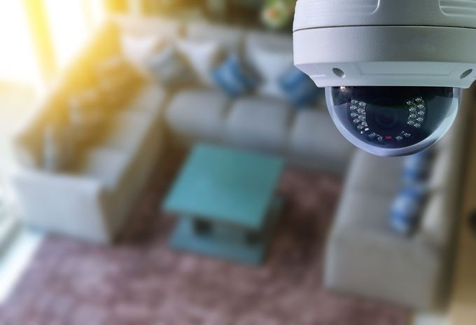 Una telecamera di sicurezza a cupola inquadra un soggiorno sfocato con un divano, un tavolino e un tappeto.