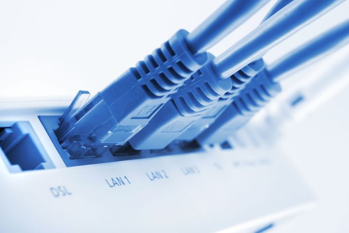 Diversi cavi Ethernet blu collegati alle porte LAN di un router bianco.