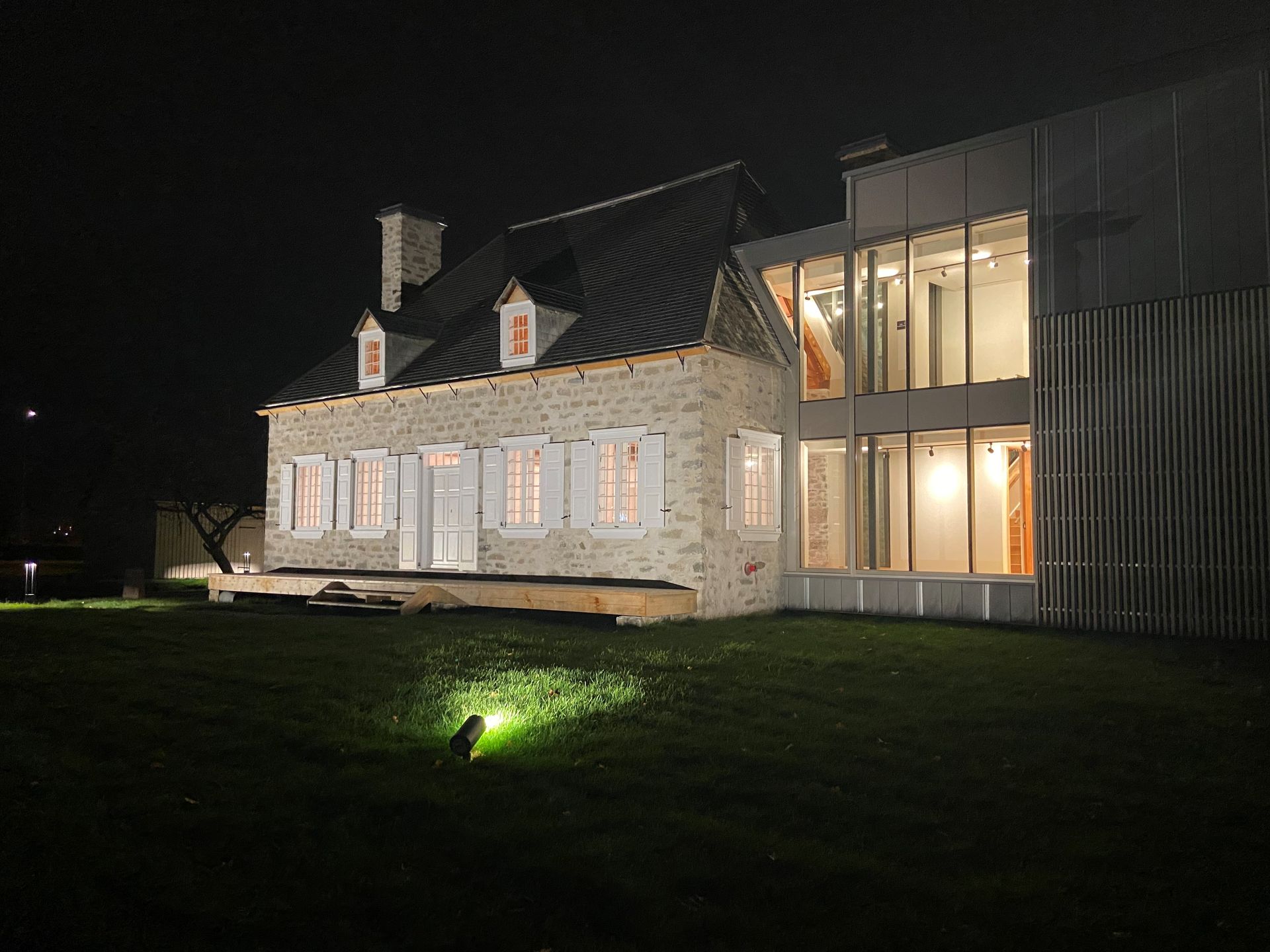 Une grande maison avec beaucoup de fenêtres est éclairée la nuit.