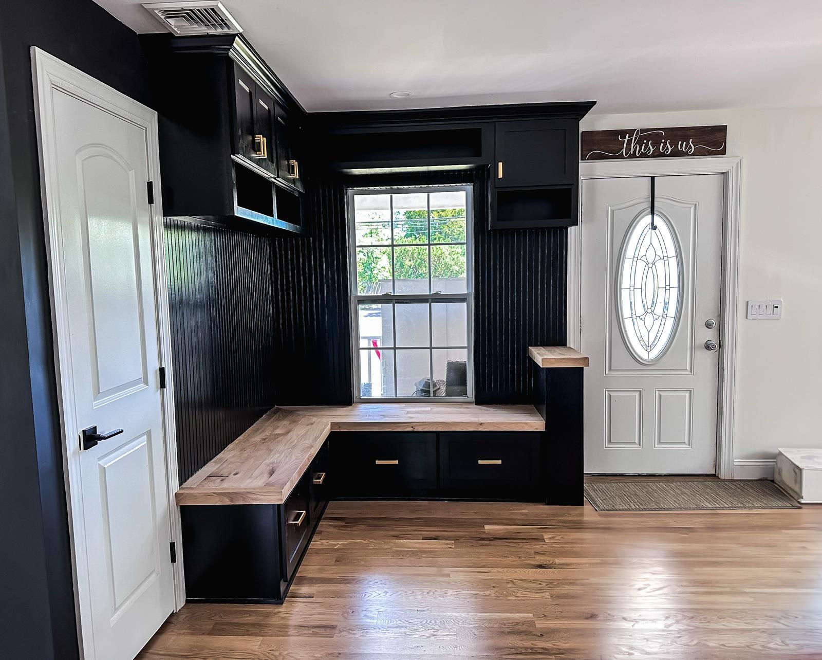 Interior view of a black built-in bench with storage, window, and white door with an oval glass panel.