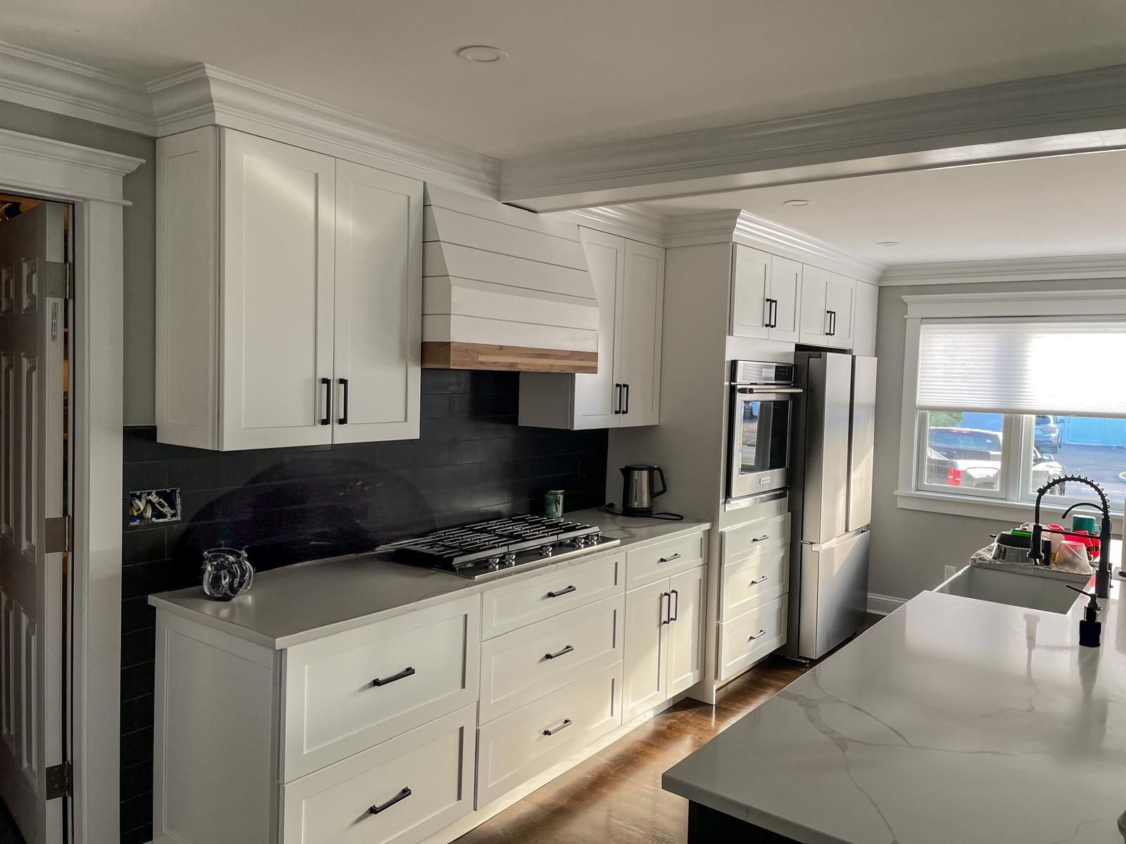 White kitchen with dark backsplash, appliances, and island.