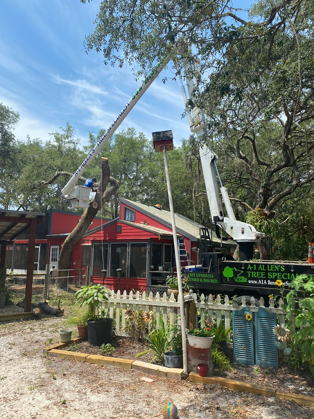 Fire truck ladder and crane equipment beside a red building in a leafy outdoor area