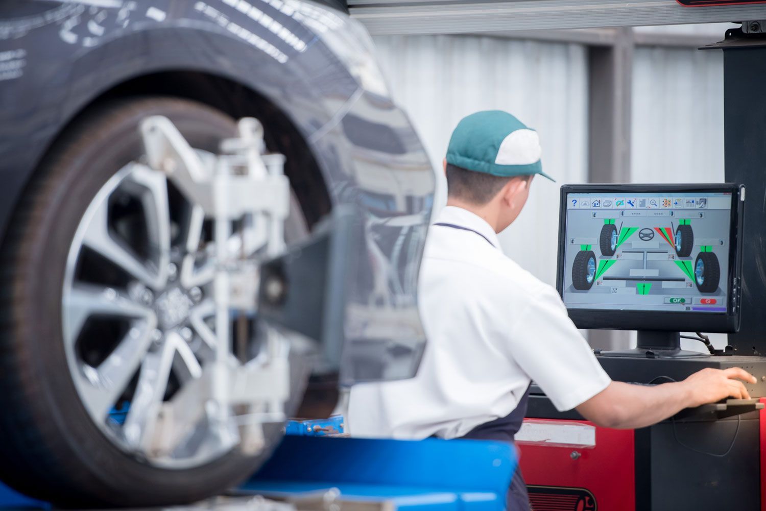 Technician inspecting a car wheel on a computer screen in an auto shop
