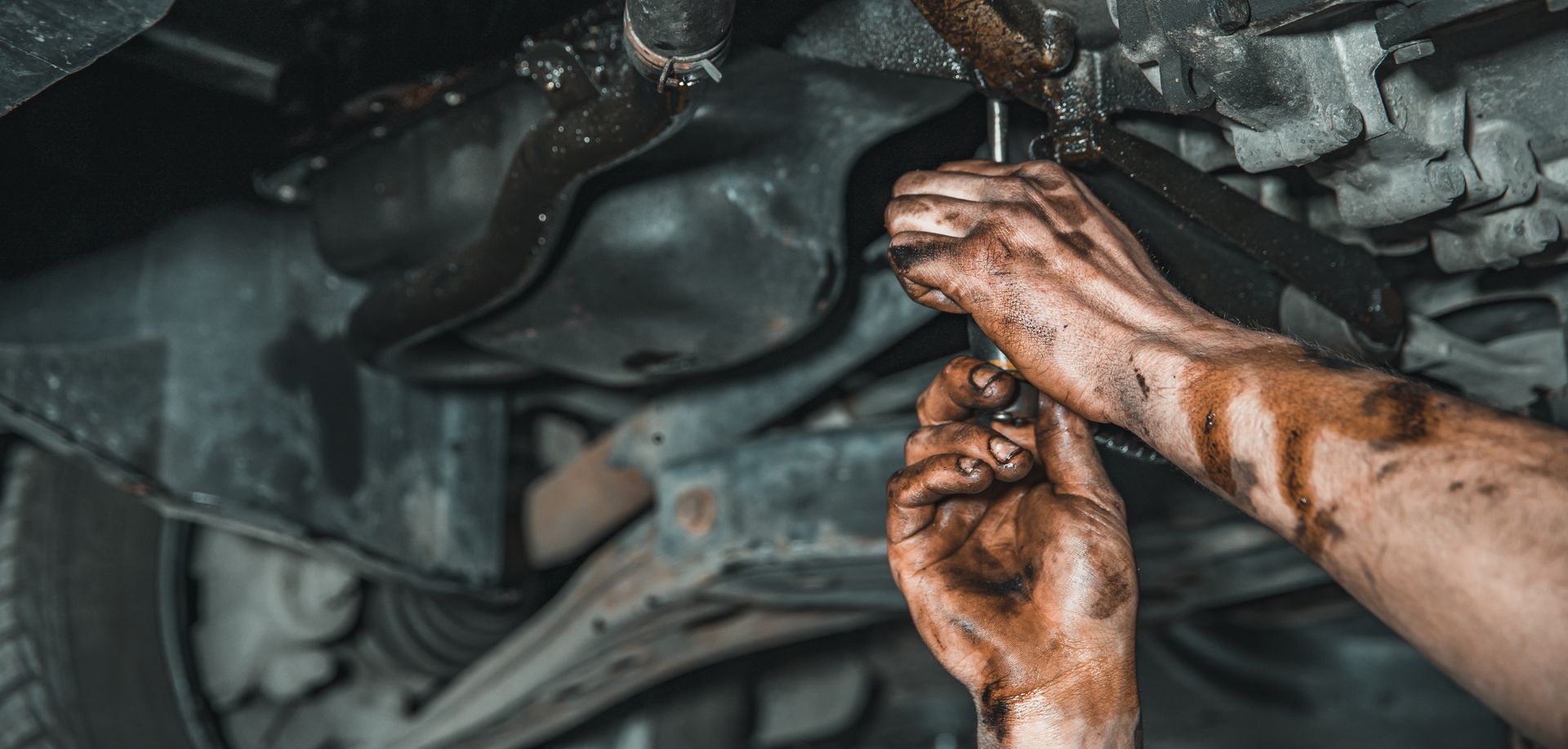 Mechanic working under the hood of a car in an auto repair shop
