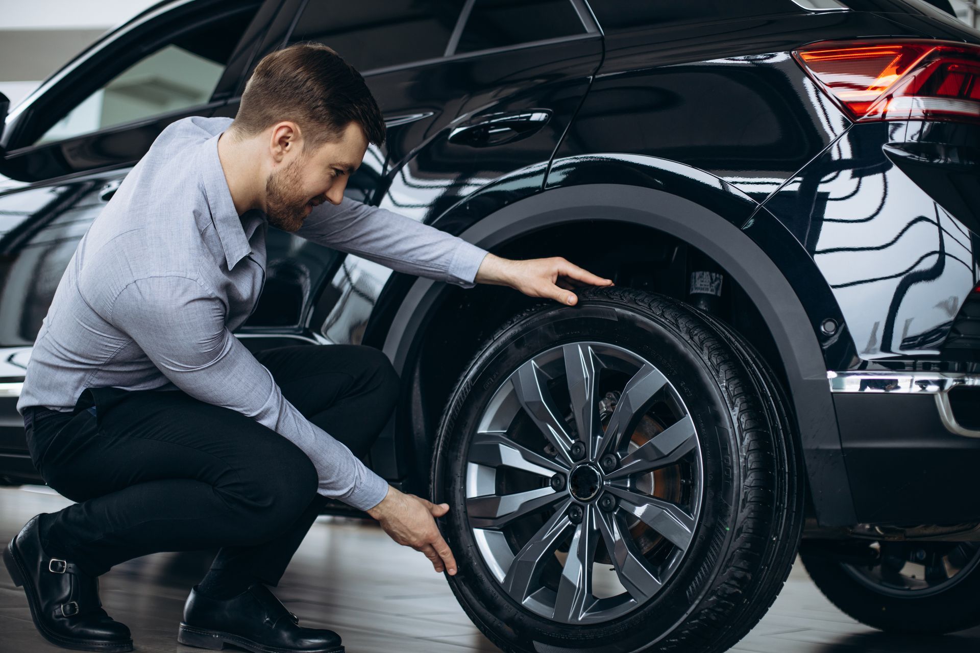 Mechanic inspecting a tire in a garage, wearing gloves and a cap