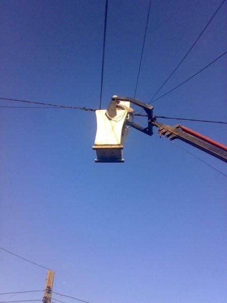 Elevador de cesta utilitaria contra un cielo azul, con líneas eléctricas en lo alto