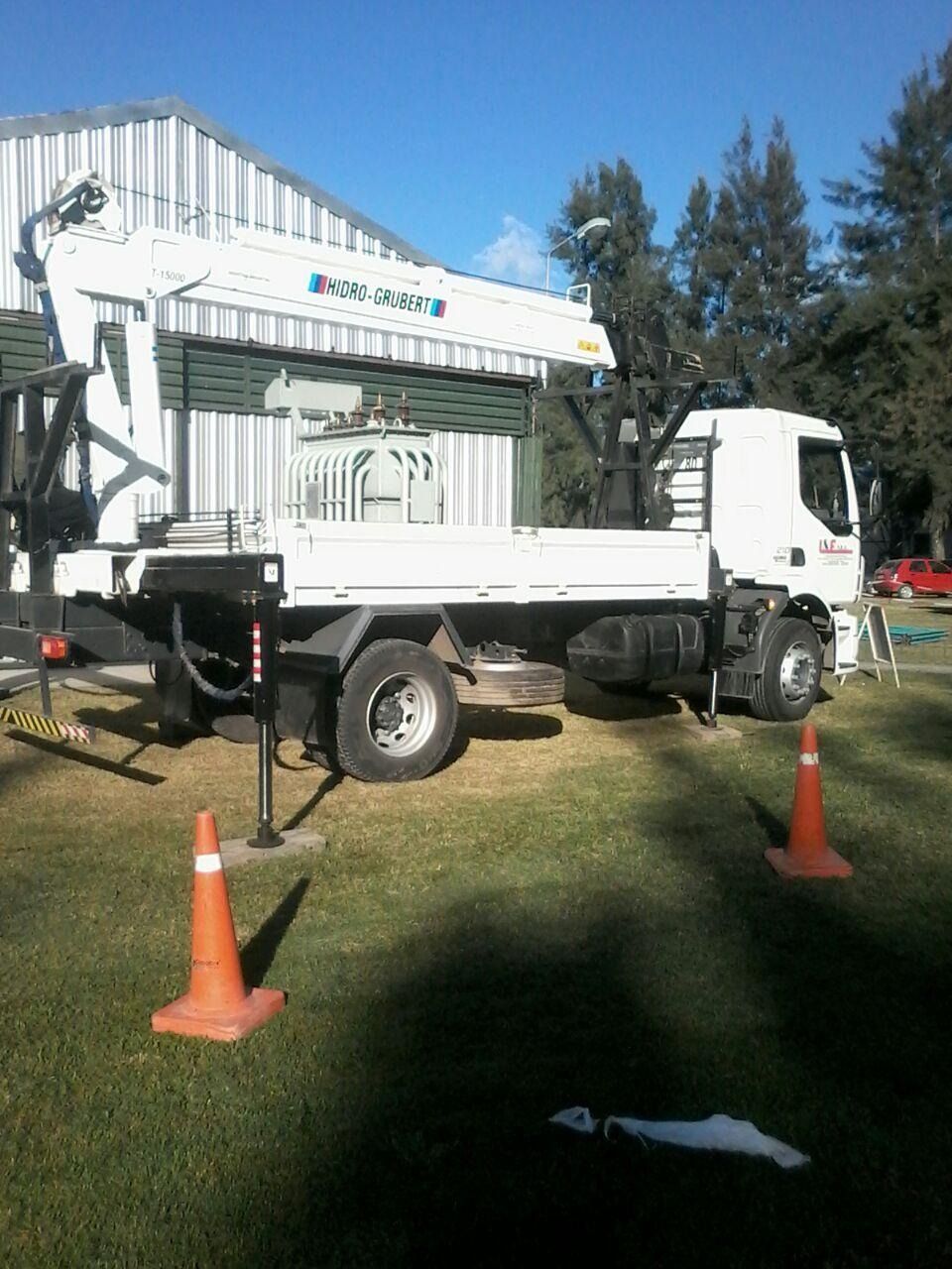 Camioneta utilitaria blanca estacionada sobre el césped junto a una casa, con conos de tráfico naranjas en primer plano.