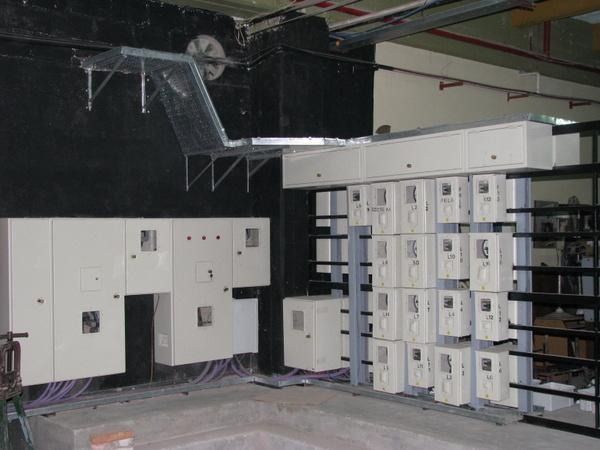 Sala eléctrica industrial con grandes paneles y armarios de control blancos a lo largo de las paredes.