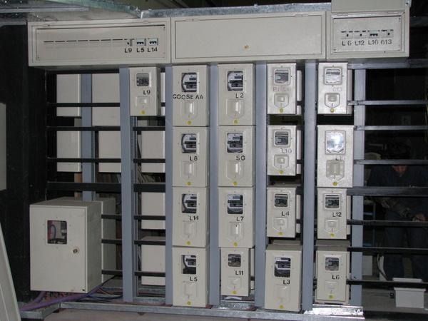 Fila de paneles eléctricos grises y contadores montados en una pared de una sala de instalaciones industriales
