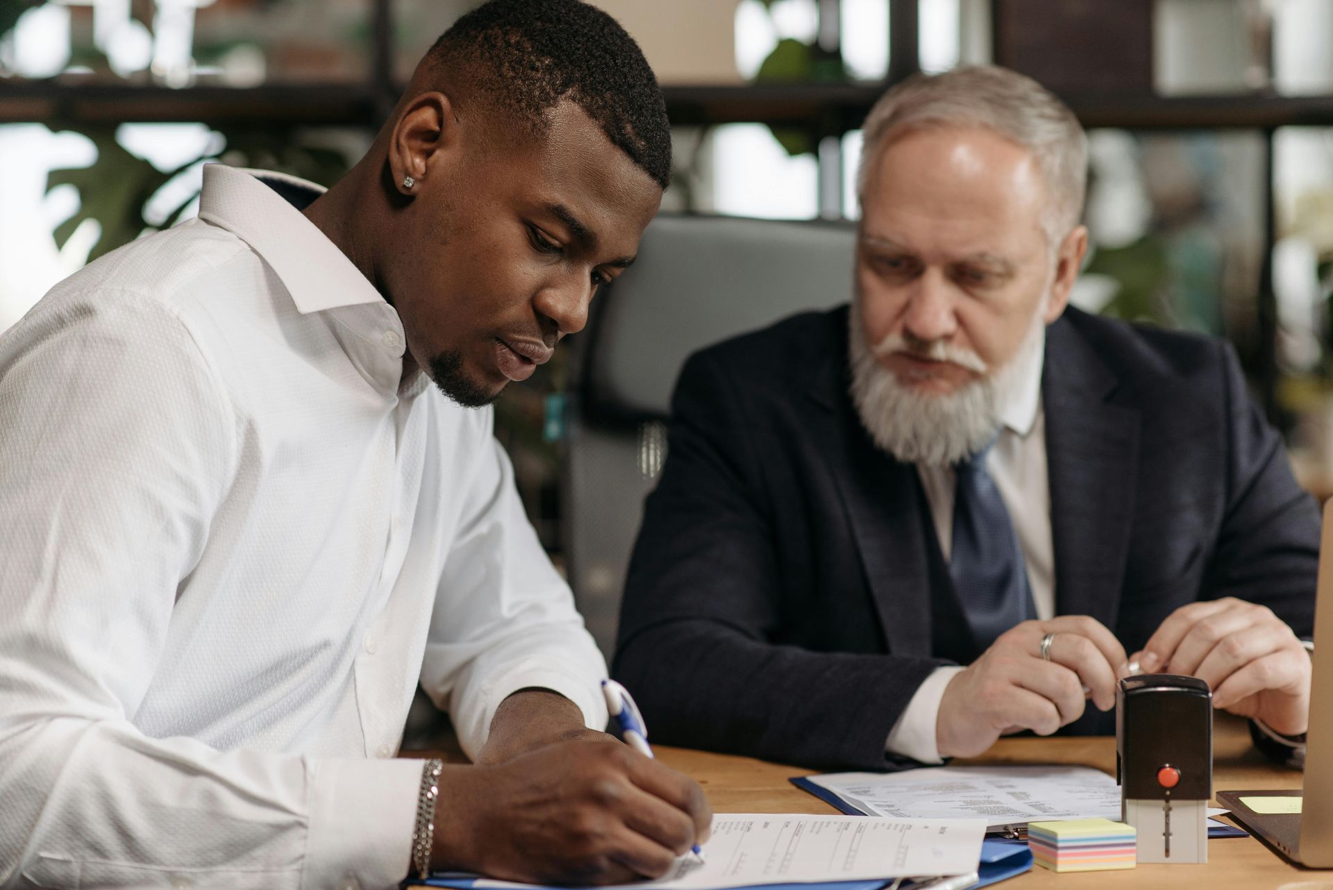 Two people reviewing documents and writing notes at a table in an office.