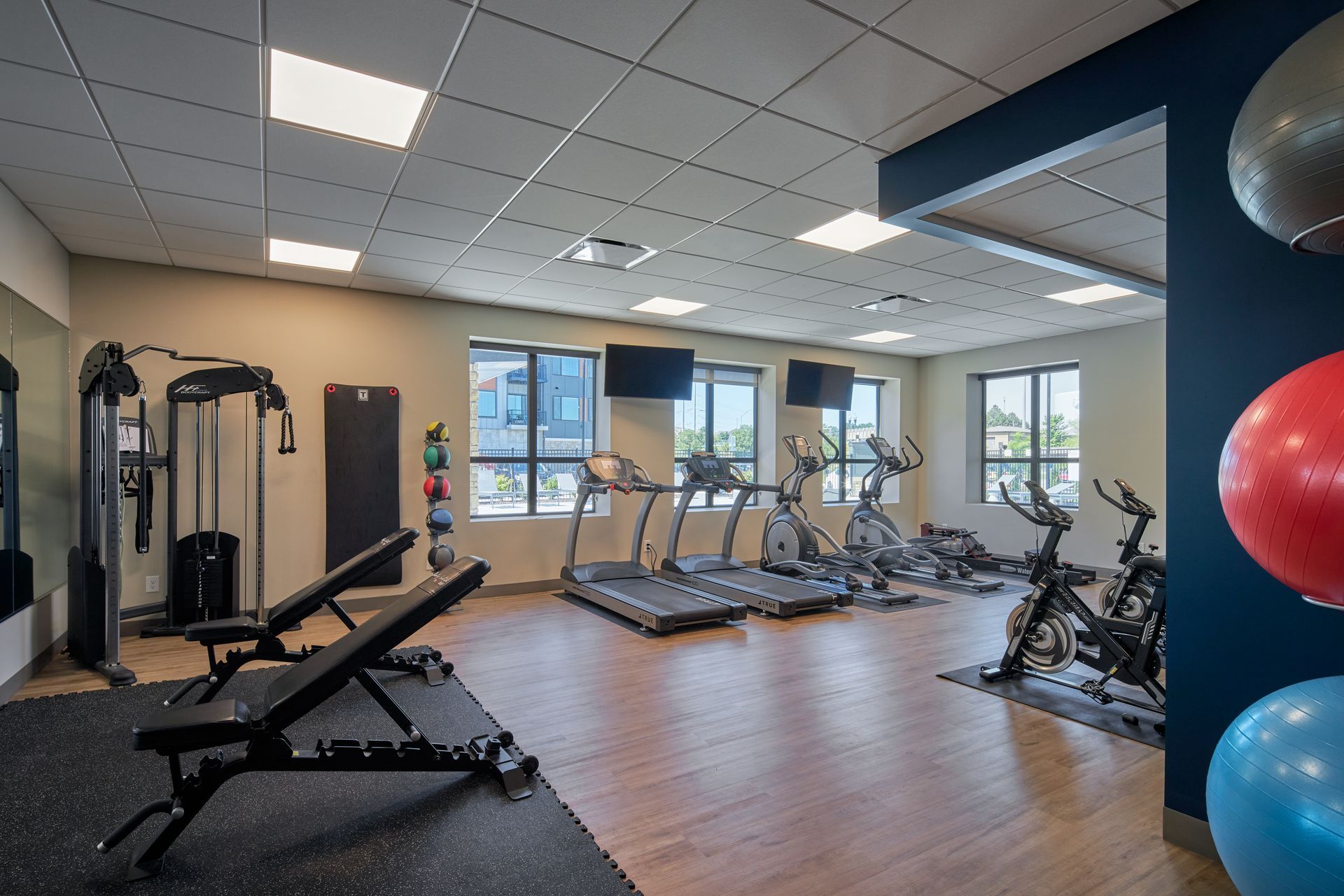 Gym with exercise equipment. Treadmills, weights, bikes, and medicine balls are visible.