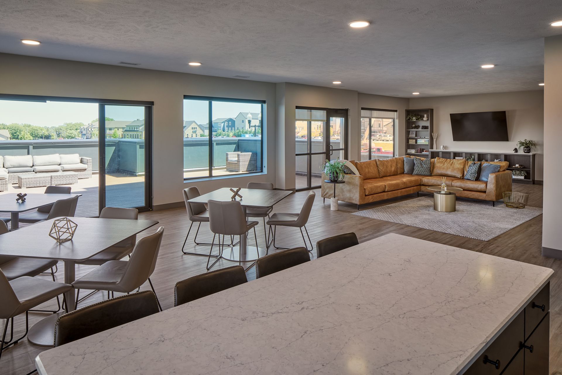Spacious, modern living area with large windows, dining tables, seating area, and outdoor deck access.