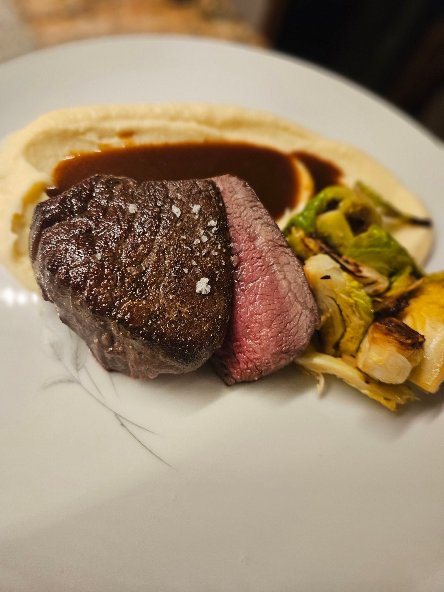 Plated steak with sauce and roasted vegetables on a white plate