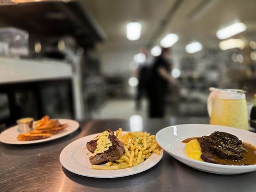 Three plated dishes on a restaurant counter with a blurred kitchen background.