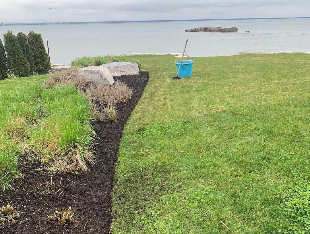 A lawn with a mop and bucket in it and a view of the ocean.