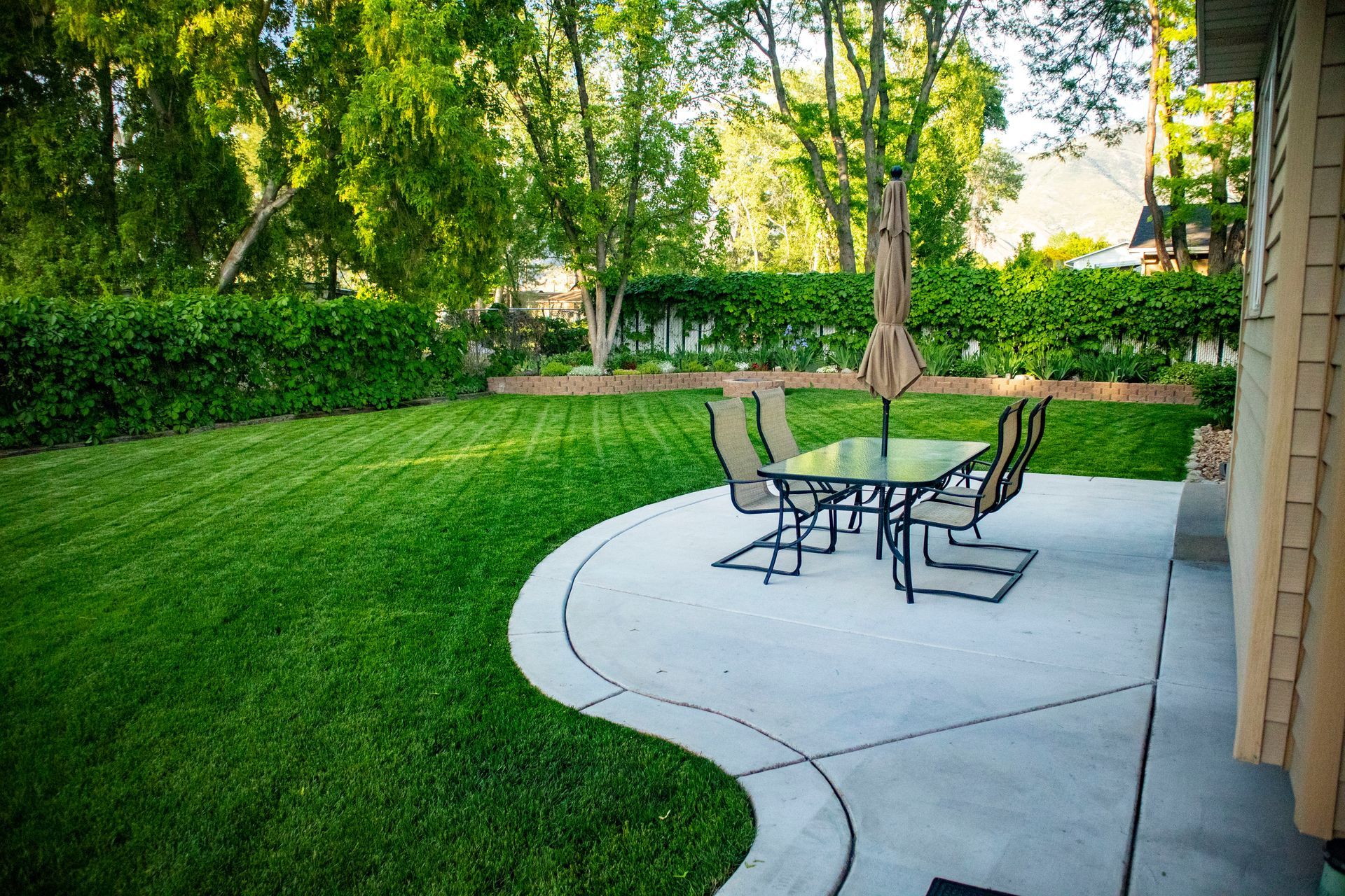 There is a patio with a table and chairs in the backyard.