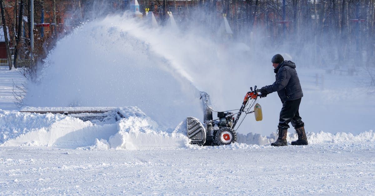 A man is using a snow blower to clear snow from the ground.