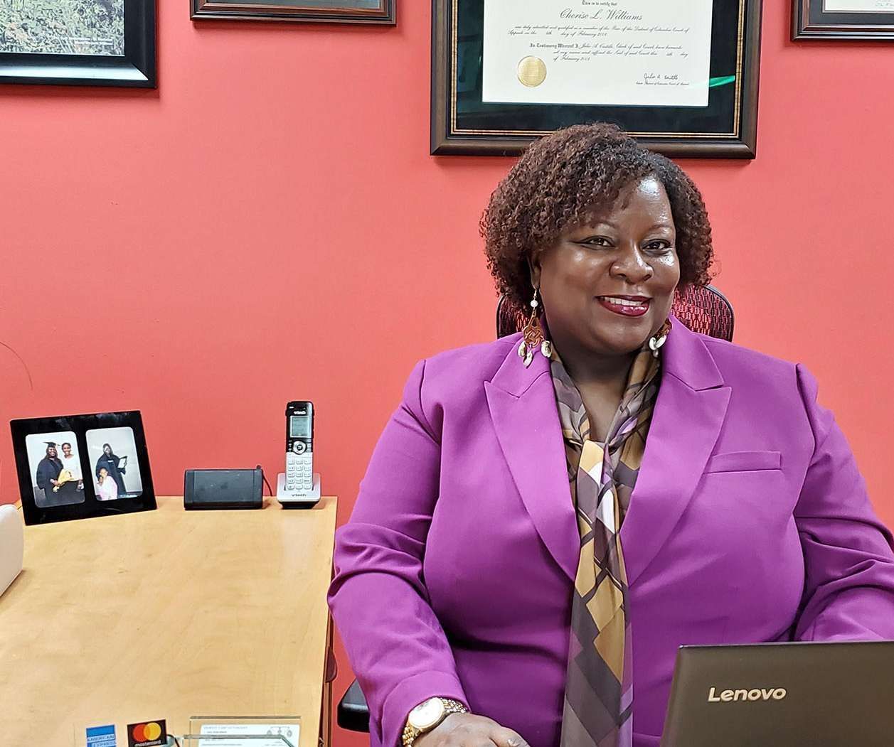 A woman in a purple suit is sitting in front of a lenovo laptop