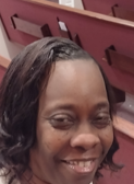 A close up of a woman 's face smiling in front of a red wall.