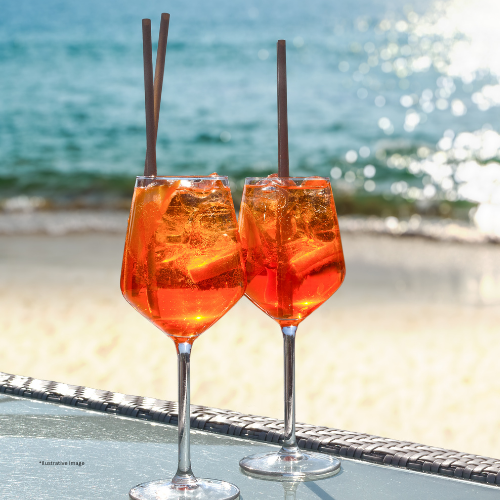 Two glasses of orange drink with straws on a table on the beach