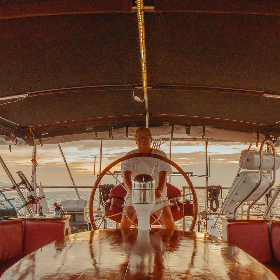 A large sailboat with red sails is floating on top of a body of water in Thailand.