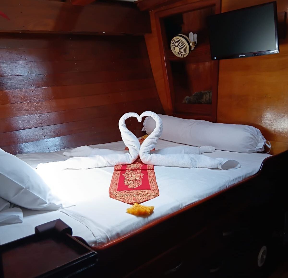 A bed with two towels shaped like swans on it