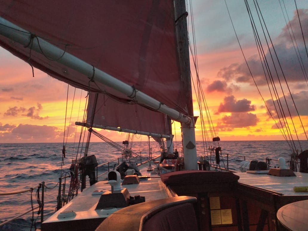 A sailboat is sailing in the ocean at sunset.