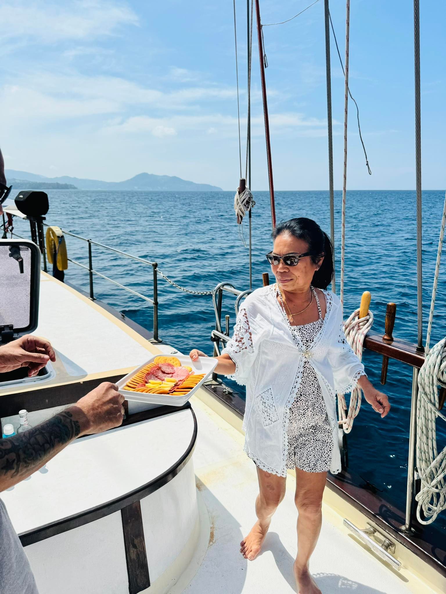 A woman in a white dress is standing on a boat in the ocean.