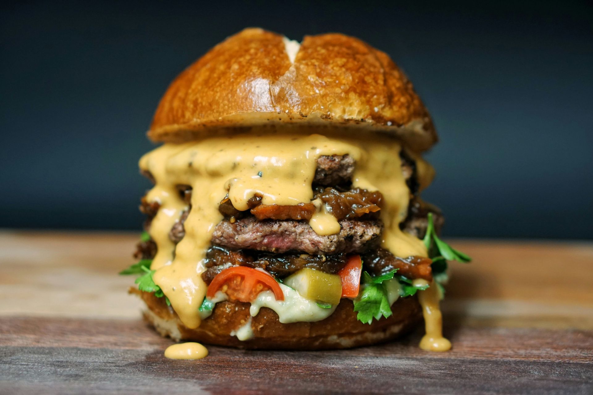 A close up of a hamburger on a wooden table.