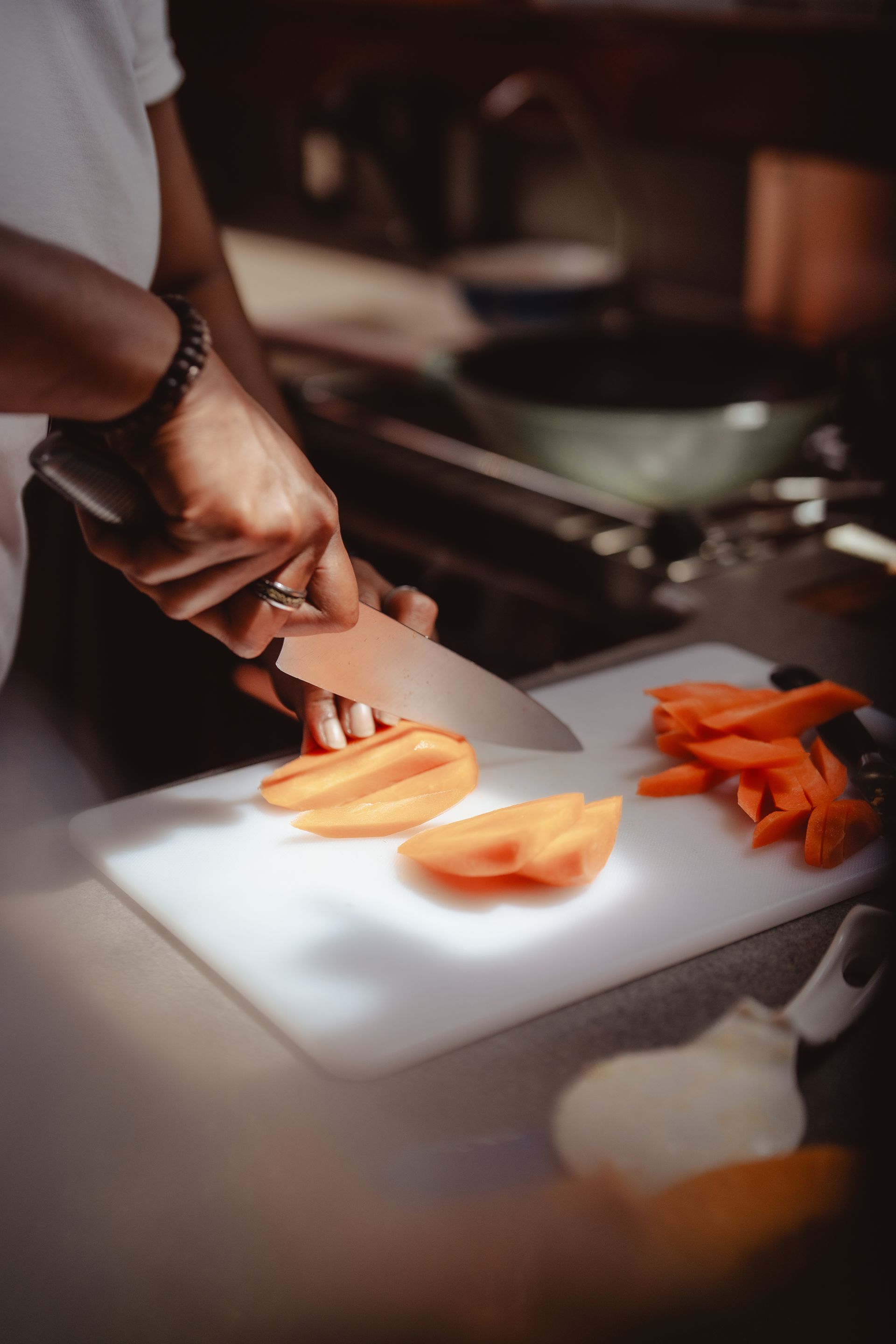 A person is cutting carrots on a cutting board in a kitchen.