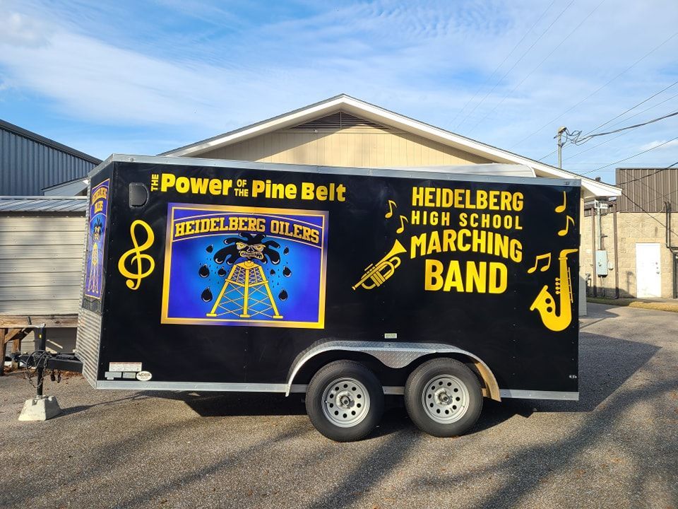 A black trailer for the Heidelberg High School Marching Band, featuring a logo, musical notes, and instrument graphics.