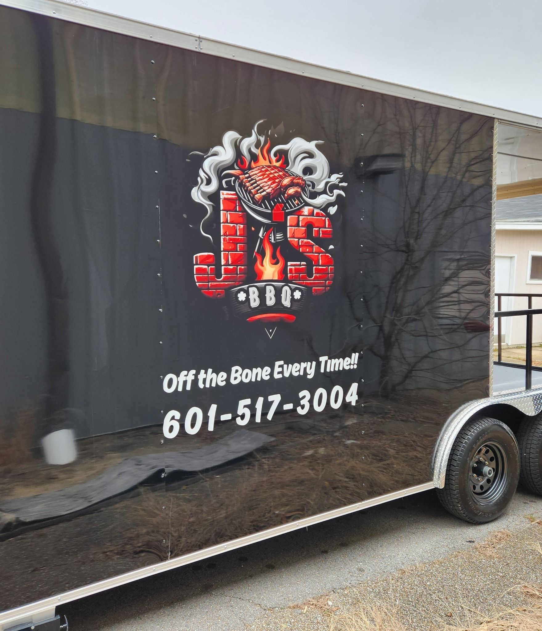 Side view of a dark food trailer with the J&S BBQ logo, slogan 