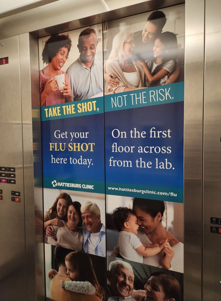 An elevator door advertisement promoting flu shots at the UnityPoint Clinic, located on the first floor across from the lab.