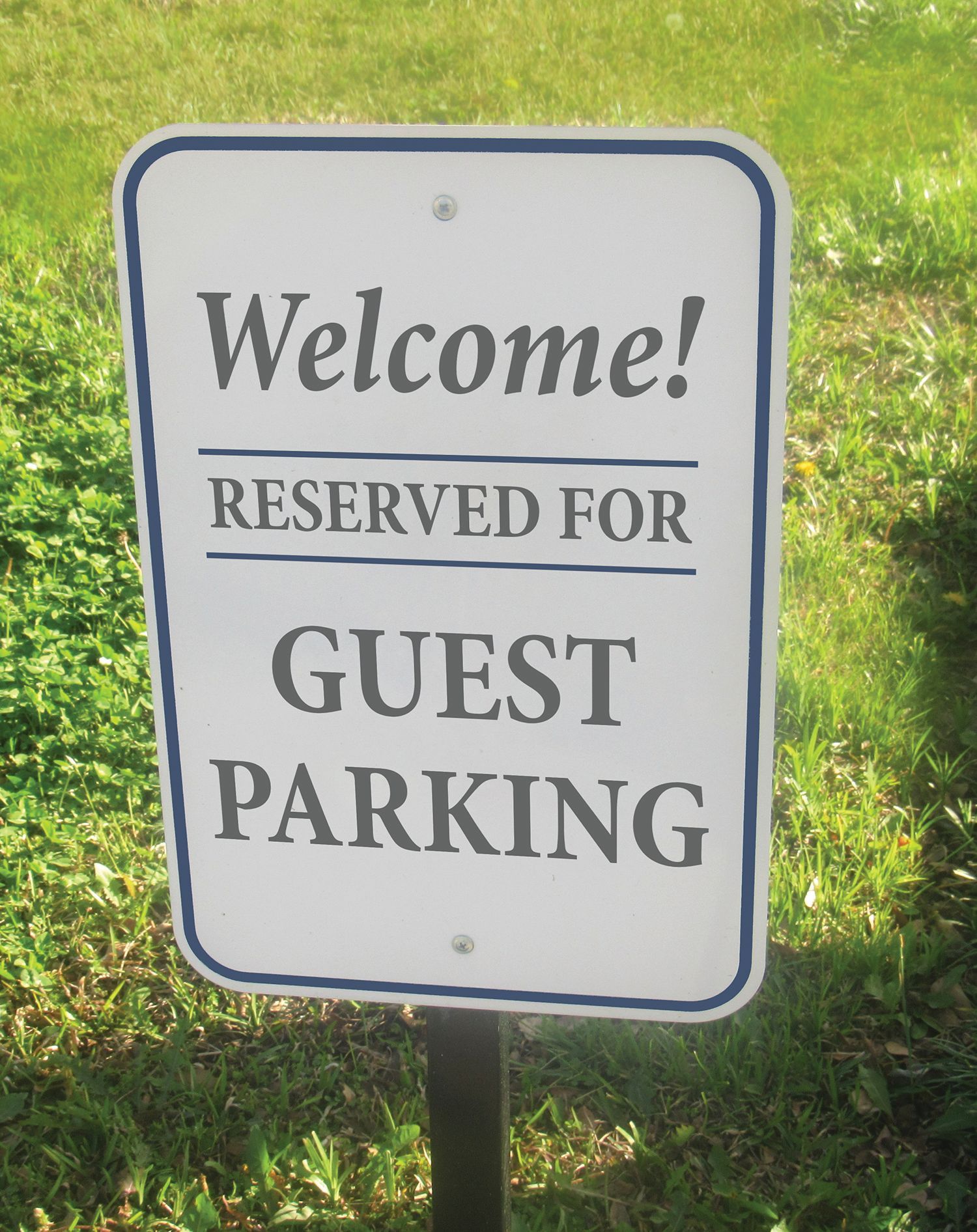 A rectangular sign with a blue border on a grass background that reads,