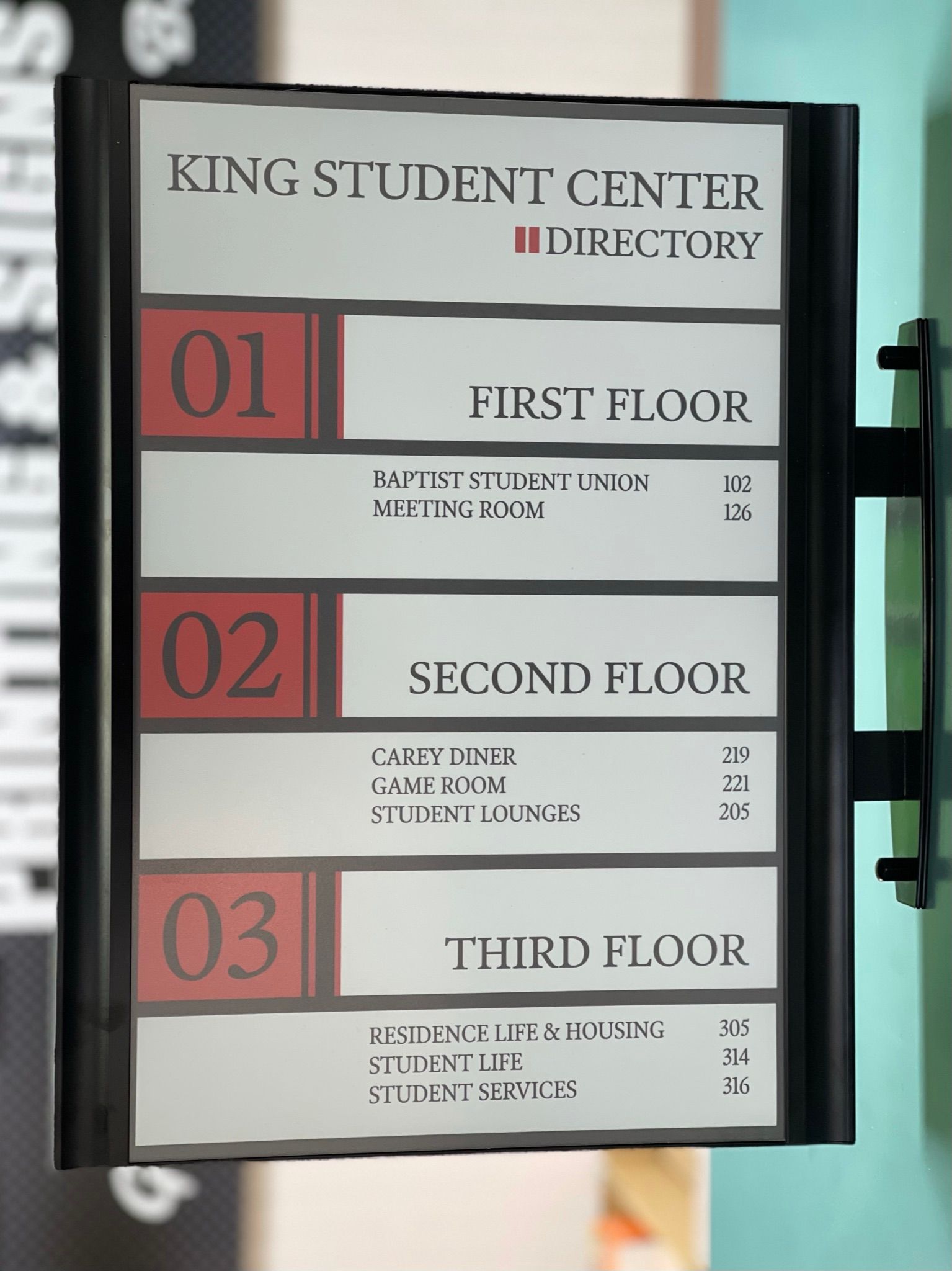 King Student Center directory sign listing floors 1-3 with room numbers on a vertical black wall-mounted frame.