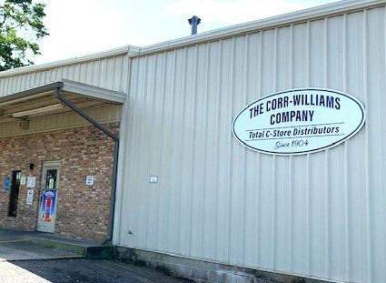 The Cobb-Williams Company warehouse, featuring a brick entrance, metal siding, and an oval company sign on the wall.