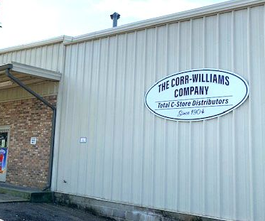 The Corr-Williams Company sign on a light-colored, ribbed metal warehouse wall with a partial brick exterior entrance.