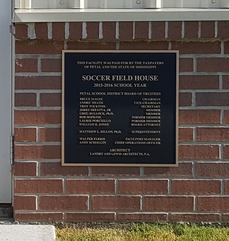 A black plaque on a brick wall titled