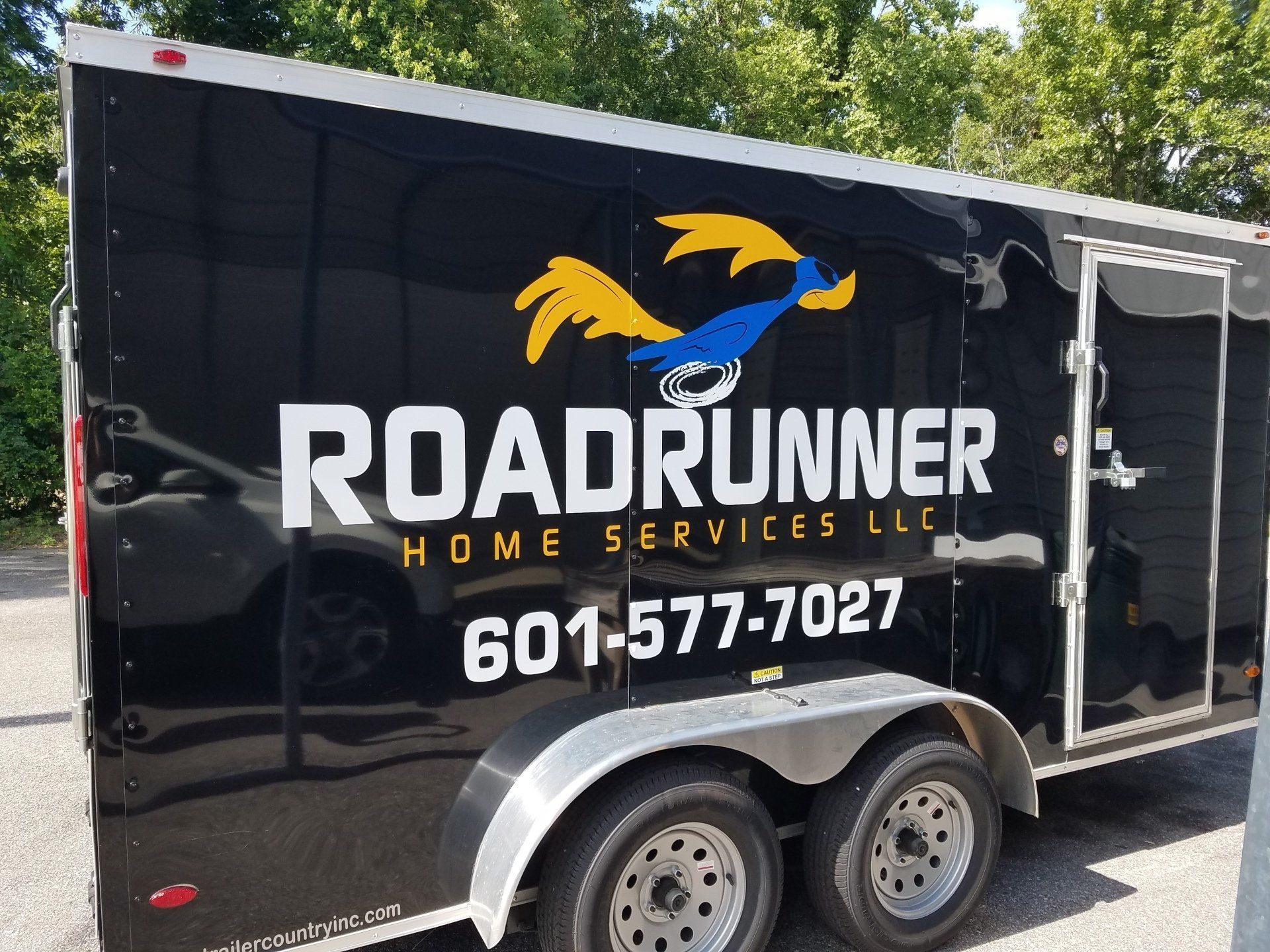 A black trailer with a blue and yellow roadrunner logo, the text 