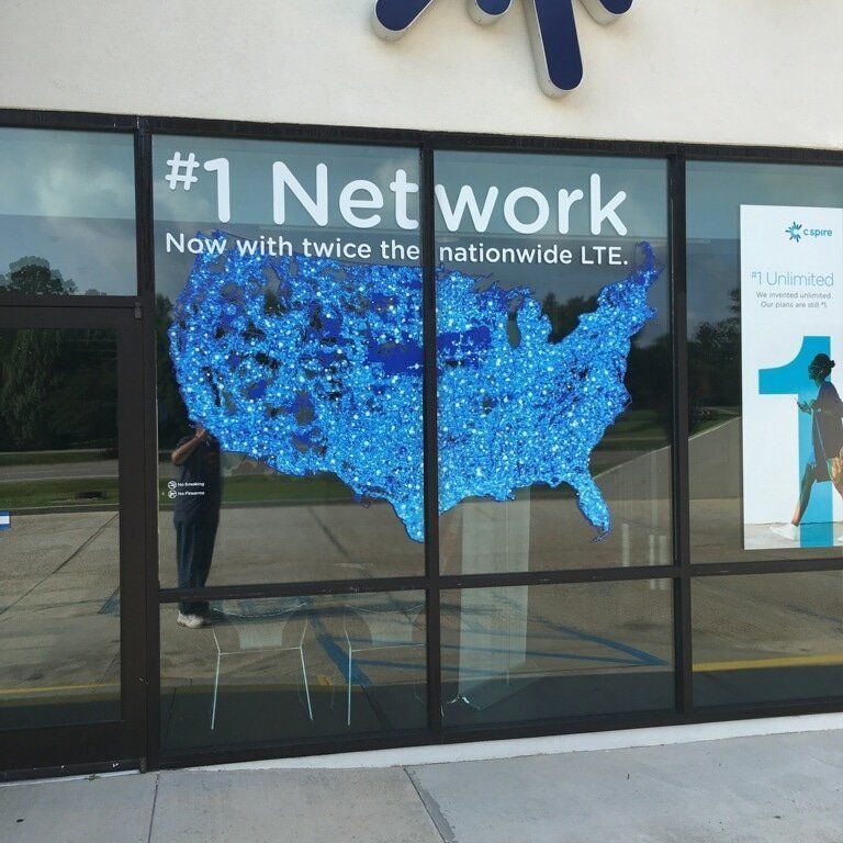 A store window display features a map of the United States covered in blue dots, advertising a 