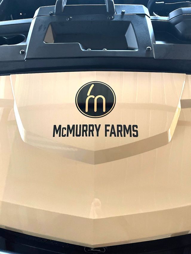 A cream-colored vehicle hood features a circular logo with a gold 
