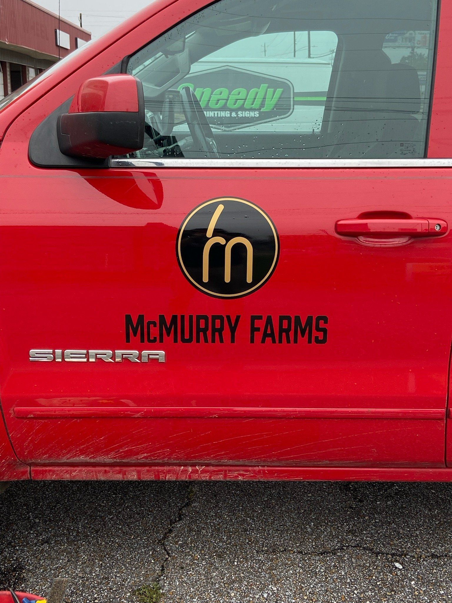 A red truck door displays the McMurry Farms logo, featuring a gold stylized 