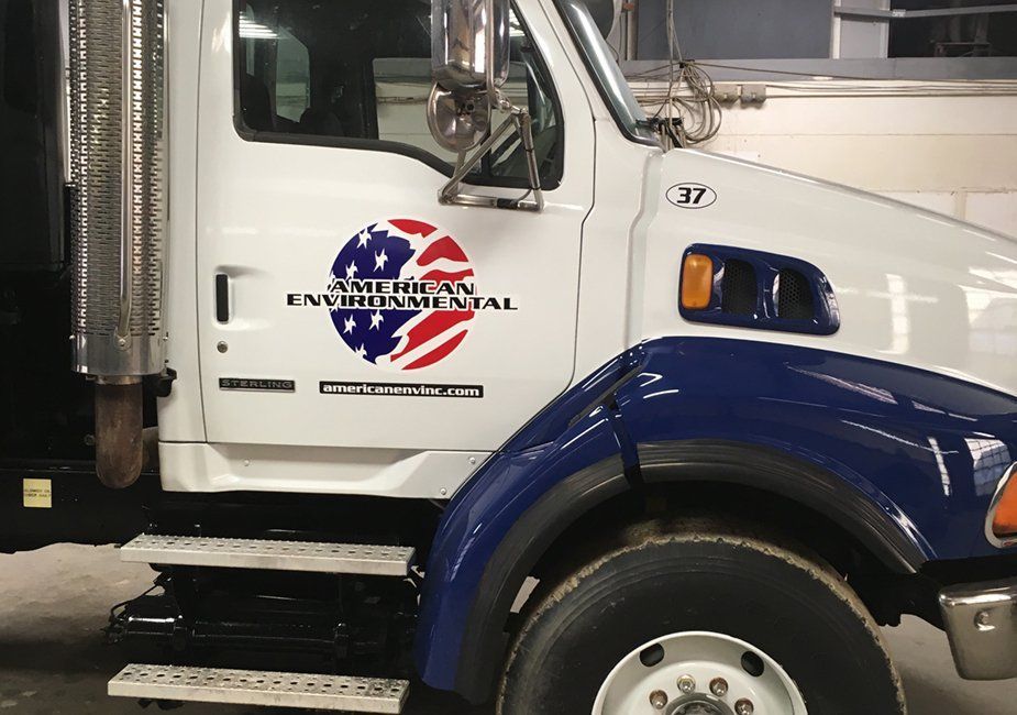 A white truck featuring a circular logo with an American flag design and the text 