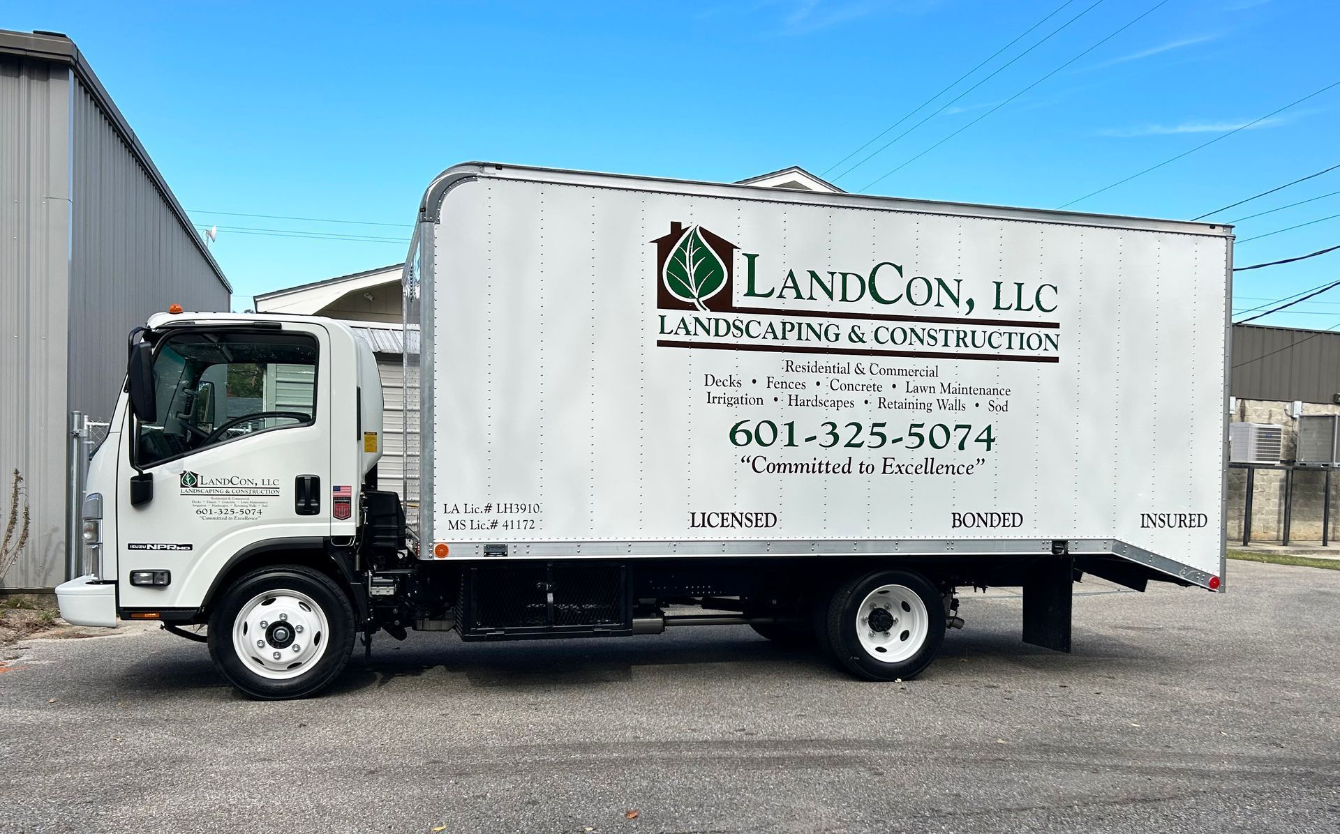 A white box truck parked on a gravel lot features the 