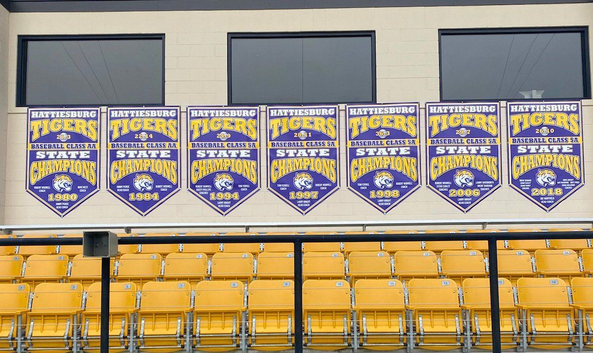 Seven championship banners for the Pittsburg Tigers hanging above rows of yellow stadium seats.