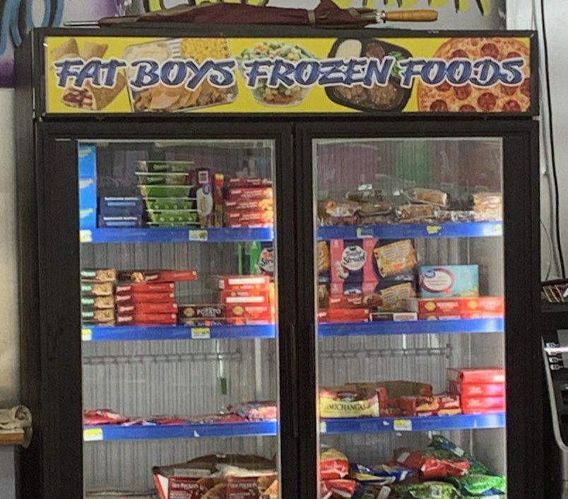 A commercial double-door refrigerator filled with packaged frozen foods under a 