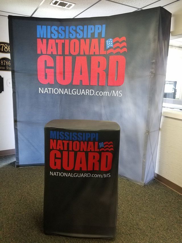 Mississippi National Guard backdrop and branded podium set up in an indoor office space.